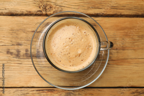 Cup of aromatic coffee on wooden table, top view