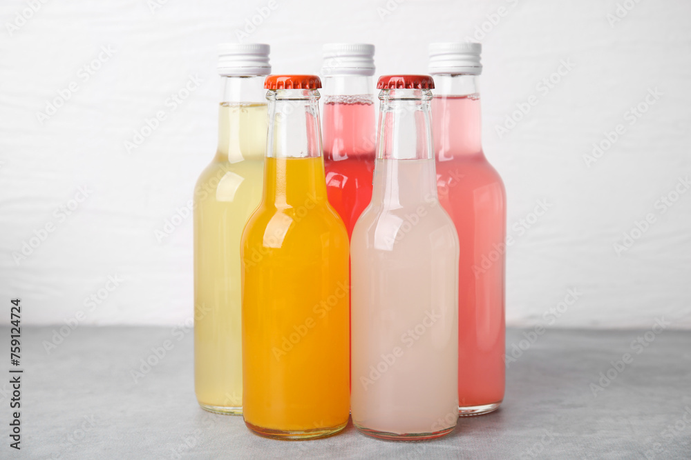Delicious kombucha in glass bottles on grey table against white background