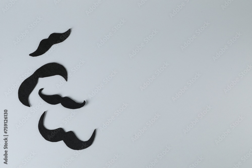 Fake paper mustaches on grey background, flat lay. Space for text Fake paper mustaches on grey background, flat lay. Space for text