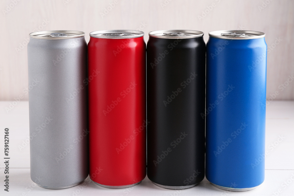 Energy drinks in colorful cans on white wooden table