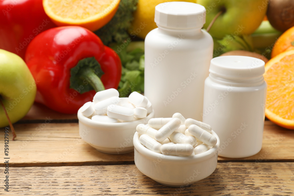 Dietary supplements. Plastic bottles, pills in bowls and food products on wooden table