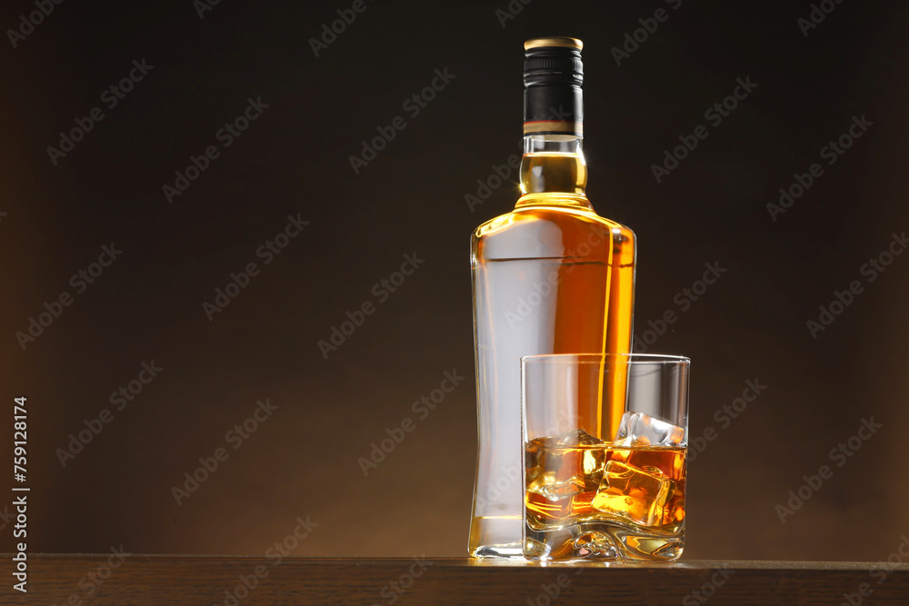 Whiskey with ice cubes in glass and bottle on table, space for text Whiskey with ice cubes in glass and bottle on table, space for text