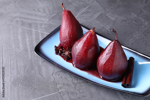 Tasty red wine poached pears and spices on grey table, closeup photo