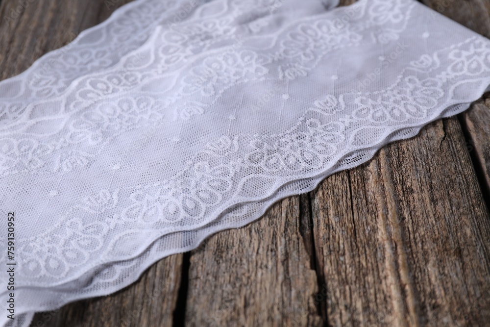 White lace with beautiful pattern on wooden table, closeup