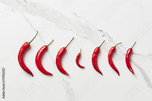 Red chili peppers lying in row on marble background photo