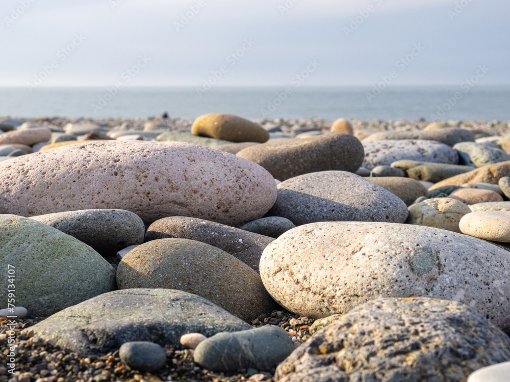 Gray sand and stones close-up on the beach. Stone in the foreground. Beach in winter. Sea coast soil. Gray sand and stones close-up on the beach. Stone in the foreground. Beach in winter. Sea coast soil.