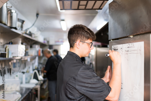 Chef writing needed ingredients on kitchen list