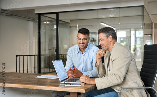 Stock exchange market traders investors working on financial trading charts analysis. Two happy busy business men analysts consulting on digital finance forecast using laptop in office. Copy space.