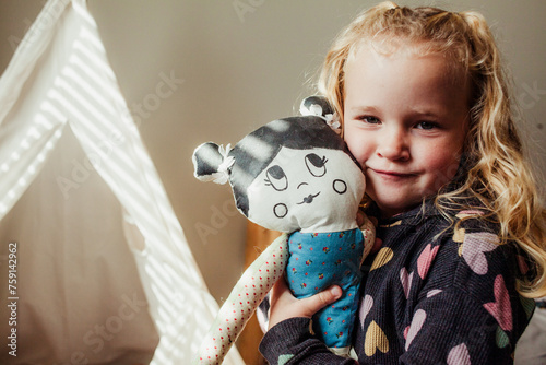 Girls cuddles a cloth doll in against face 2. photo