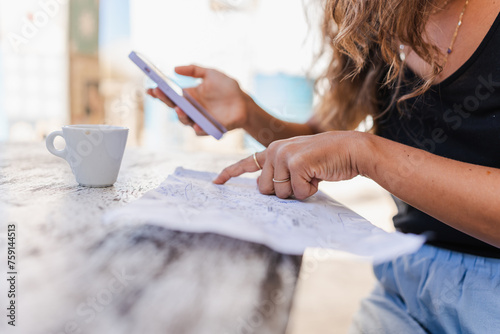 unrecognizable woman using smartphone and writing notes photo