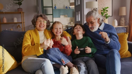 Old couple babysitting kids and using console for having fun photo
