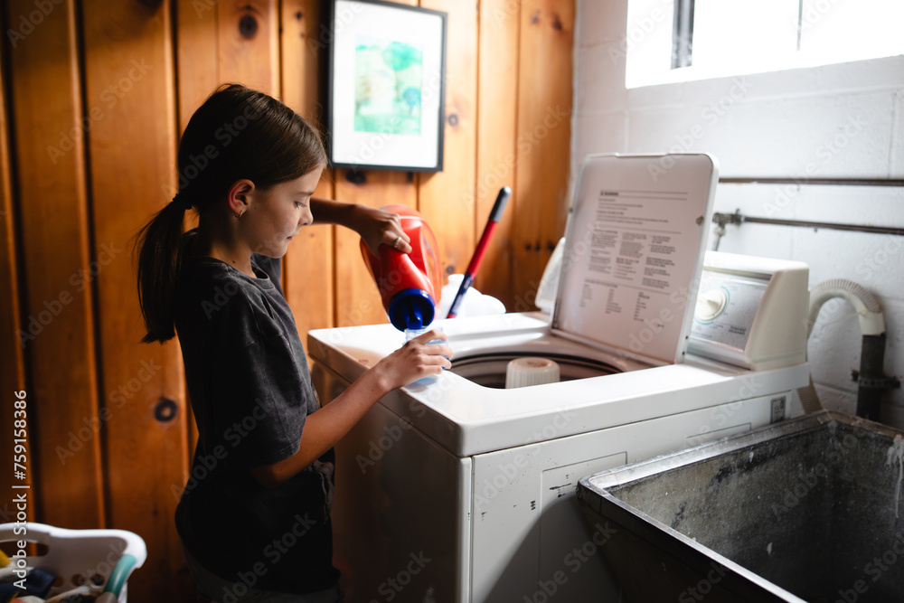 © Maria Manco/Stocksy - Tween loads washing machine with laundry