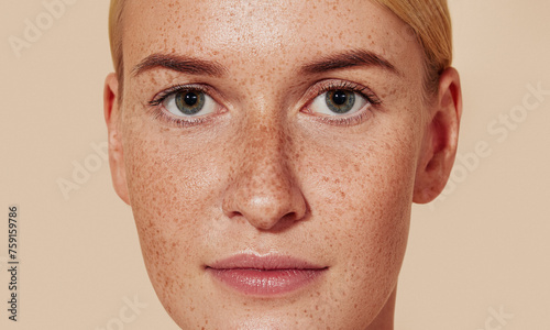 Close-up studio shot of a young female with freckles. Portrait of natural beauty woman with smooth skin against pastel backdrop.
