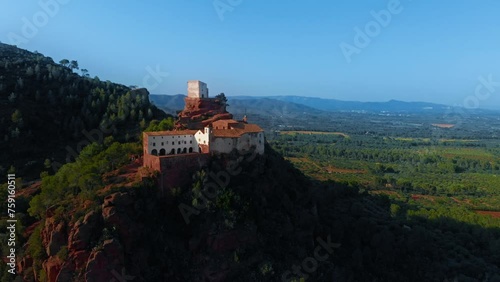 Historical building on hilltop, embraced by trees in natural landscape. Aerial view of medieval castle or manastery on top of mountain and countryside valley below photo