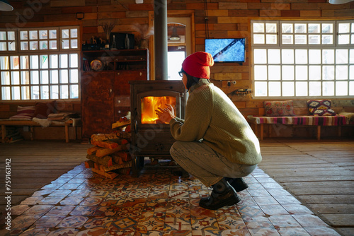 Woman in a red hat is sitting by the fireplace photo