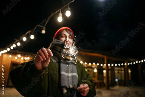 A woman stands in the evening with a sparkler in her hands photo