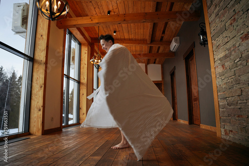 A woman is spinning wrapped in a blanket in her house photo