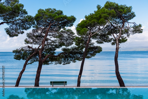 Fototapeta Naklejka Na Ścianę i Meble -  Infinity pool in luxury hotel along the promenade in coastal town Makarska, Split-Dalmatia, Croatia, Europe. Coastline of Makarska Riviera, Adriatic Sea. Dreamlike atmosphere. Vacation summer concept