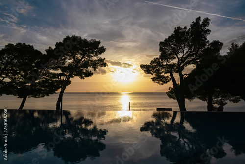 Infinity pool in luxury hotel at romantic sunset in coastal town Makarska, Split-Dalmatia, Croatia, Europe. Coastline of Makarska Riviera, Adriatic Sea. Dreamlike atmosphere. Vacation summer concept photo