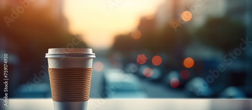 A glass cup of coffee is placed on a table by a window  casting shadows. The sunlight enhances the rich brown tint of the drinkware  creating a warm atmosphere