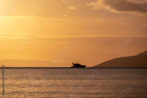 Silhouette of luxury boat during sunset at Dalmatian archipelago seen from coastal town Makarska, Split-Dalmatia, Croatia, Europe. Coastline of Makarska Riviera, Adriatic Sea. Balkans in summer
