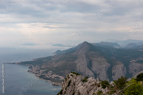 Scenic aerial view of coastal town Omis surrounded by Dinara mountains in Split-Dalmatia, South Croatia, Europe. Majestic coastline of Omis Riviera at Adriatic Sea in Balkans in summer. Wanderlust photo