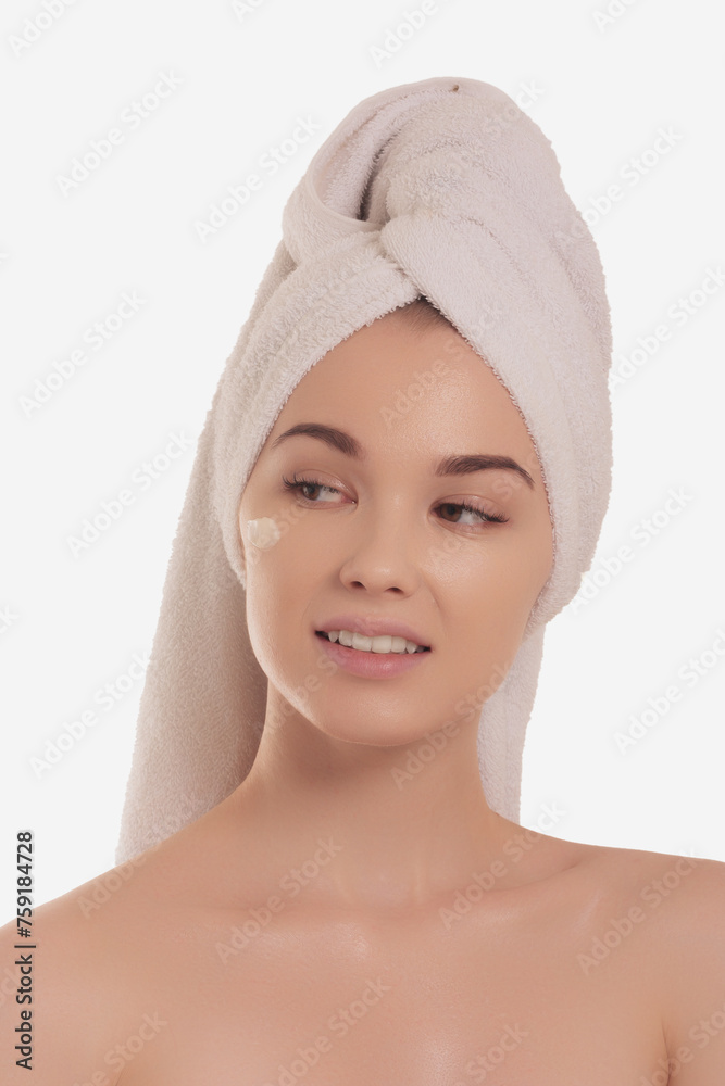 Close up cropped portrait of a young beautiful woman in bath towel smiling applying face body cream on her face for rejuvenation soft moisturizing effect. Spa beauty treatment concept. Body skin care Close up cropped portrait of a young beautiful woman in bath towel smiling applying face body cream on her face for rejuvenation soft moisturizing effect. Spa beauty treatment concept. Body skin care