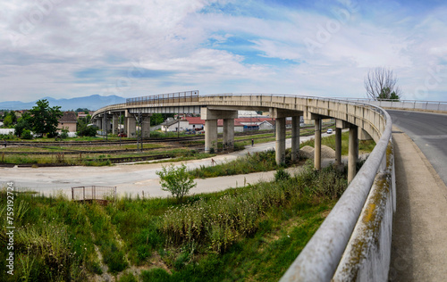 An overpass (bridge) built of concrete pillars and asphalt passes over the track through which the high-speed trains pass.