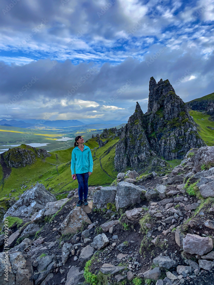 Smiling young lady is in awe of the mighty rock towers under The Storr mountain