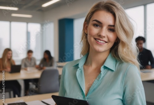 Cheerful young woman with long blonde hair in a modern office environment, her expression welcoming and pleasant.