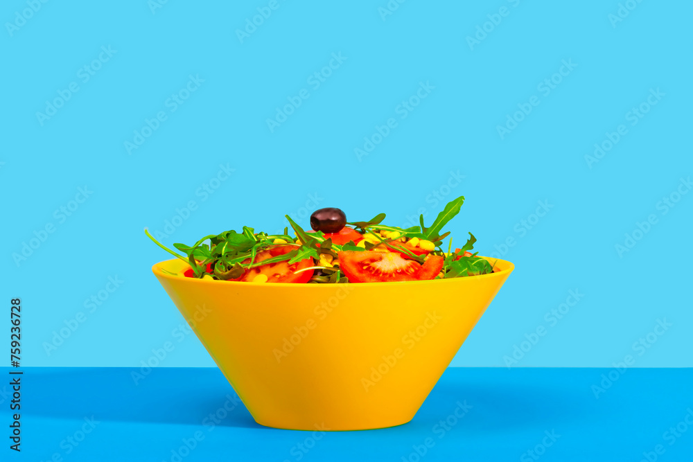 Fresh salad in a yellow bowl on a blue background Fresh salad in a yellow bowl on a blue background