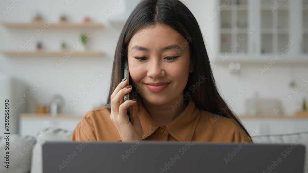 Asian Chinese multitasking businesswoman korean woman working laptop from home solve business task talk mobile phone listen information nod head agree make order delivery in kitchen talking cellphone Asian Chinese multitasking businesswoman korean woman working laptop from home solve business task talk mobile phone listen information nod head agree make order delivery in kitchen talking cellphone