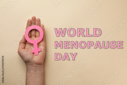 World Menopause Day. Woman holding female gender sign on beige background, top view photo