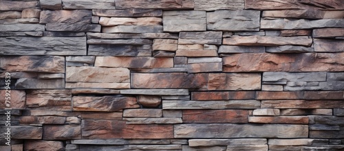 A close up of a brown stone wall made up of rectangular bricks, a composite building material commonly used in brickwork. The wall has a rich texture resembling hardwood flooring