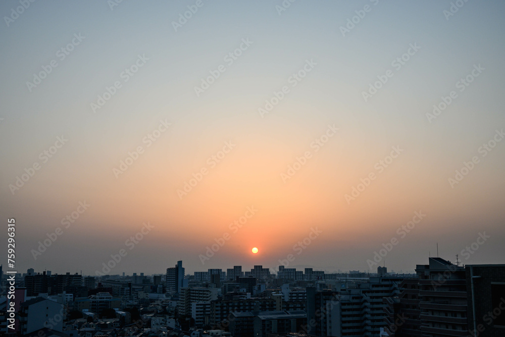 都市の夜明け。神戸市内から芦屋のビルがをのぞみ、ビルの上から朝日が昇る。
