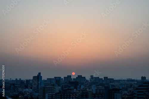 都市の夜明け。神戸市内から芦屋のビルがをのぞみ、ビルの上から朝日が昇る。