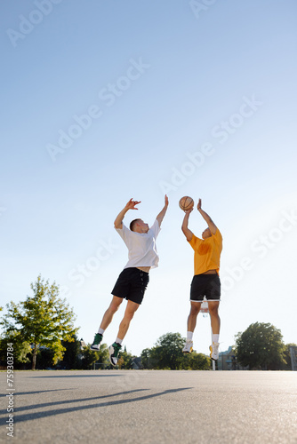 Two men playing one-on-one basketball together outside. photo