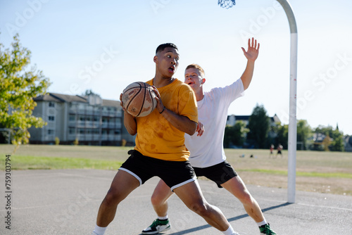 Two men playing one-on-one basketball together outside. photo
