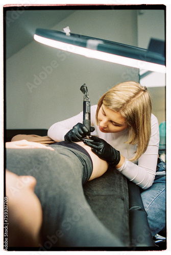 Woman carefully making a tattoo  photo