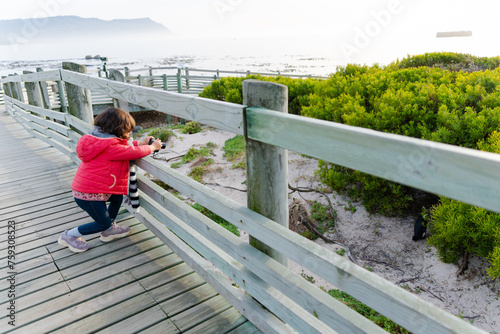 Kid taking photos to penguins. Travel to South Africa photo