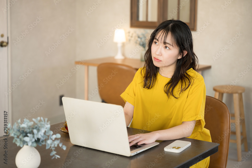 自宅やオフィスででパソコンを使う若い女性　考える悩むポーズ