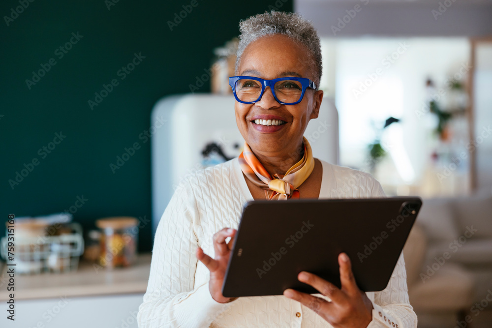 © BONNINSTUDIO/Stocksy - Cheerful woman with tablet at home © BONNINSTUDIO/Stocksy - Cheerful woman with tablet at home
