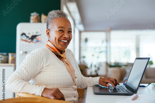 Cheerful woman working on laptop at home photo