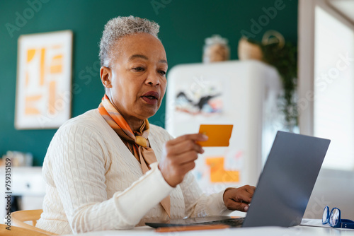 Happy female with grey hair using laptop at home photo