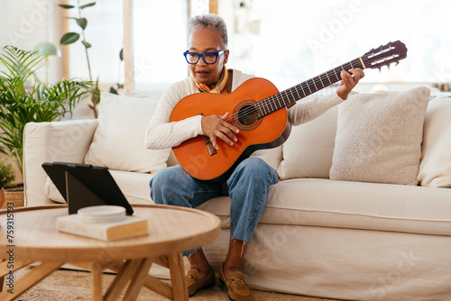 Senior woman with guitar on sofa photo