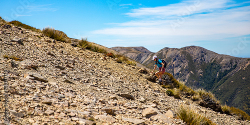 hiker girl walking on a rocky path between porters pass and foggy peak in torlesse tussocklands national park, canterbury, new zealand south island photo