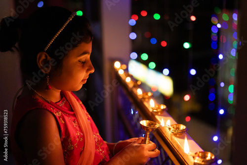 Little girl igniting oil lamps during diwali photo