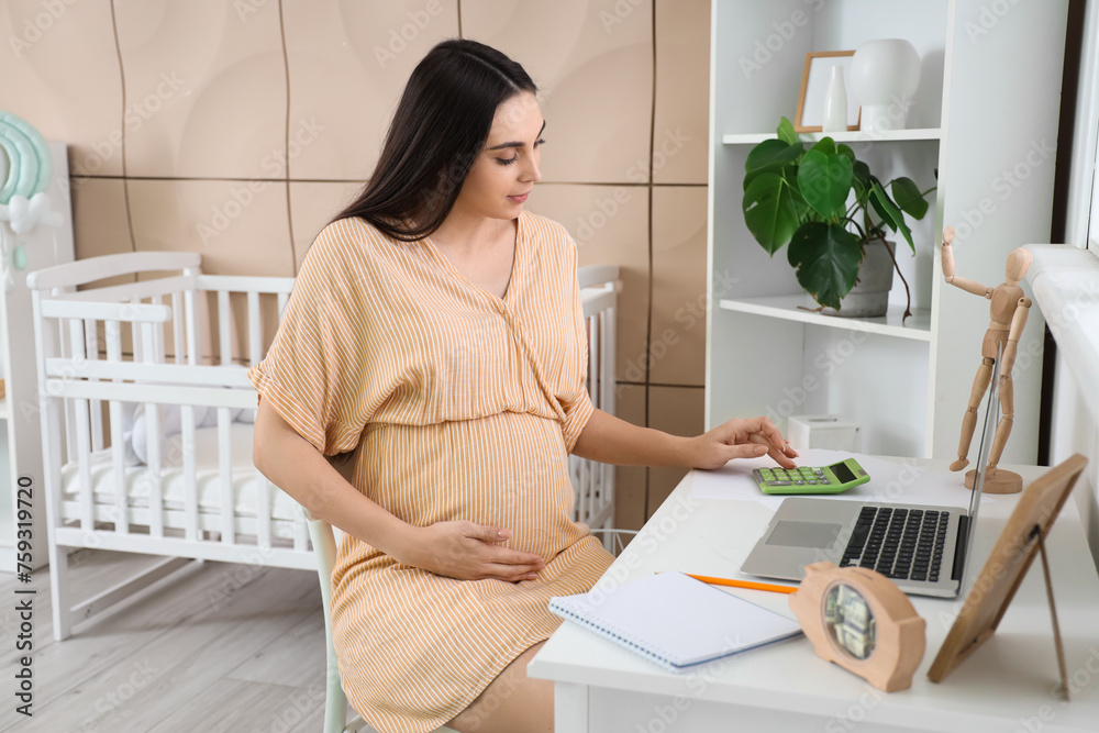 Young pregnant woman using calculator at home. Maternity Benefit concept