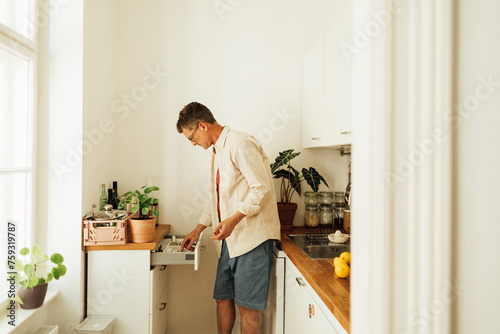 Man searching for something in kitchen drawer  photo