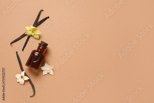 Fototapeta Naklejka Na Ścianę i Meble -  Vanilla extract in bottle with vanilla pods and flowers on beige background. Top view